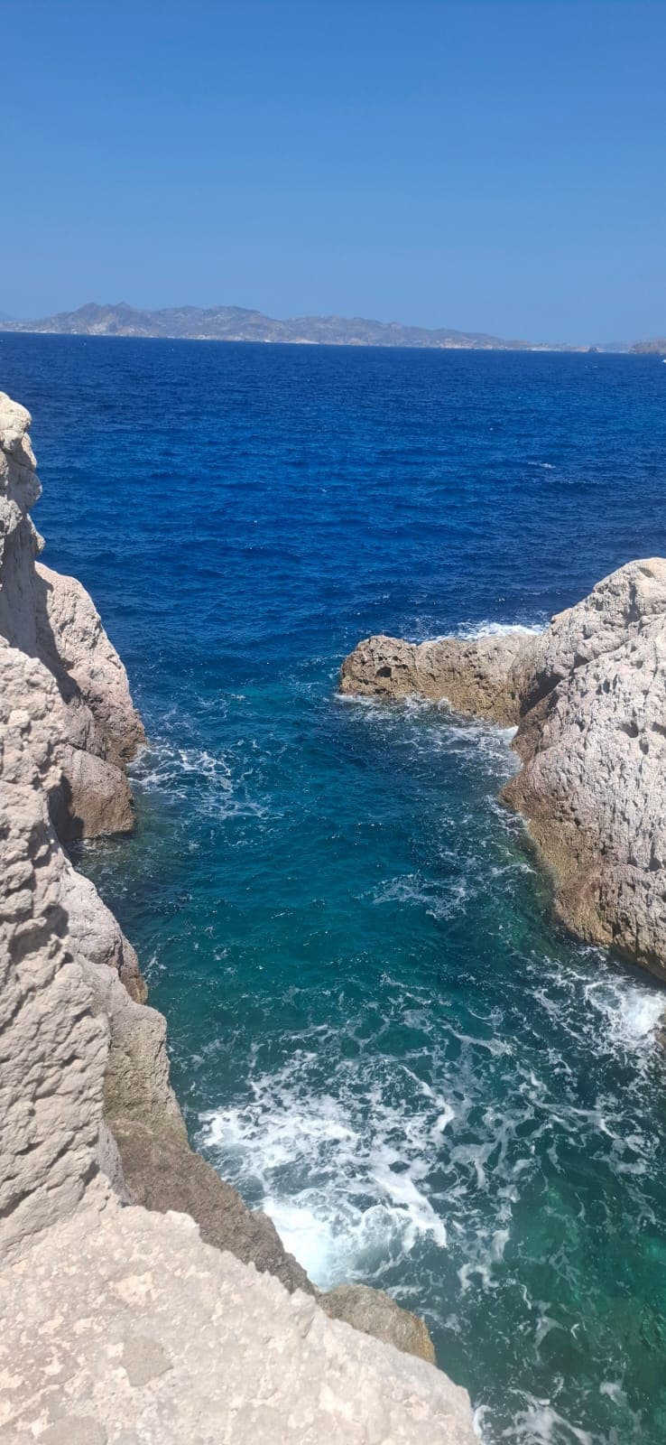 Turquoise water crashing between pale limestone rocks on the coast of Milos