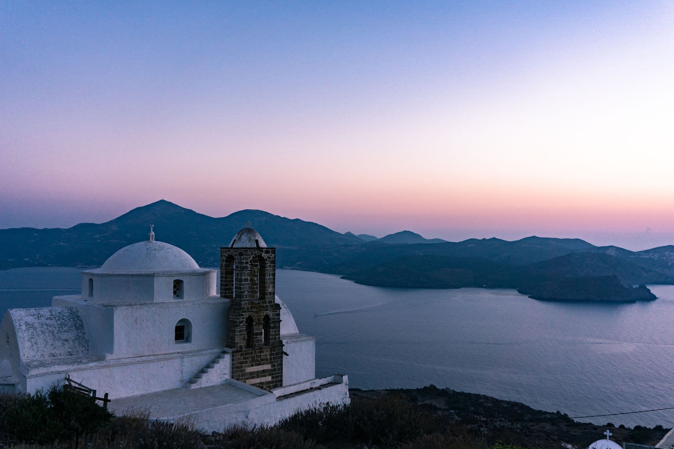 Iglesia blanca en Milos con vistas al mar al atardecer