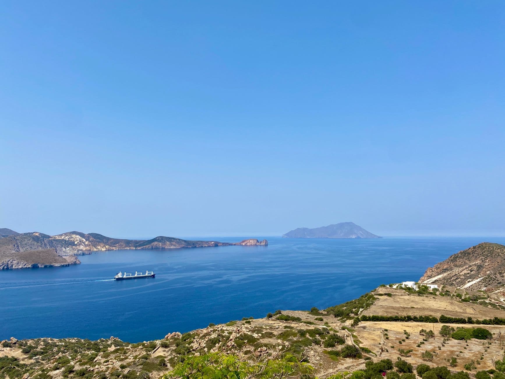 Ship passing the Milos coastline with islands on the horizon