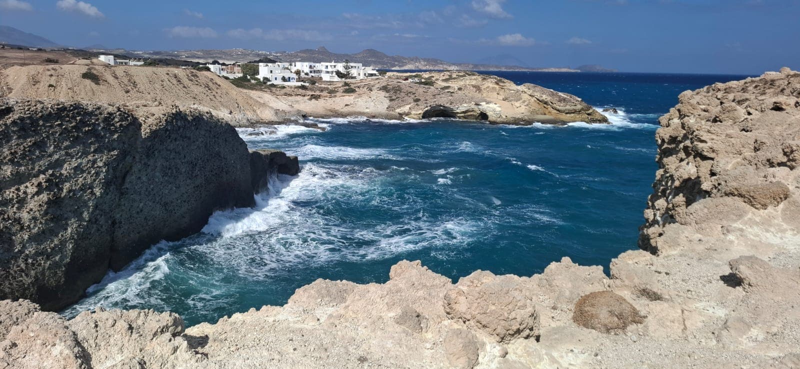Rocky cove and white village on the north coast near Pollonia, Milos