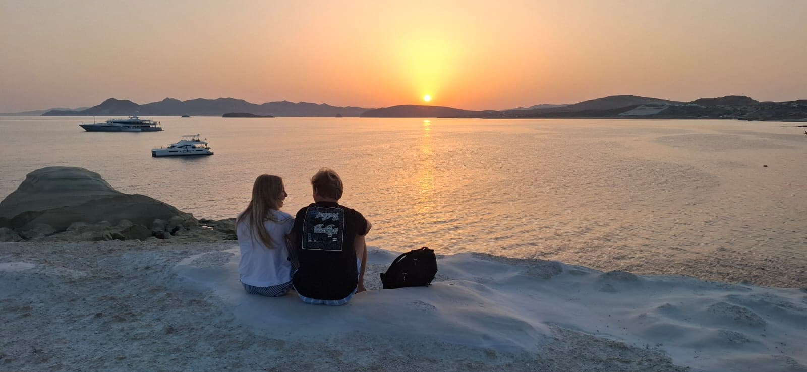 Couple watching sunset from the white rocks of Sarakiniko, Milos